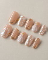 Venus close-up of glossy nude shell nails with gold metallic details