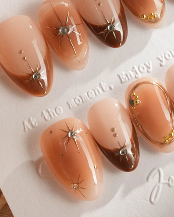 Close-up of Fall Makeup nails with brown gradient, raised gold stars, and crystal gem details