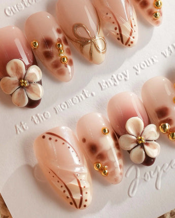Close-up of Caramel Cream nails with caramel 3D flowers and fine gold wire accents