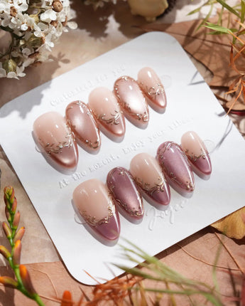 Close-up of Caramel Petal press-on nails with rose chrome French tips and gold baroque detailing