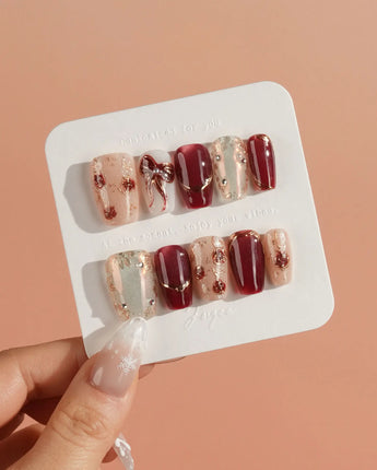 Coquette Red press-on nails with glossy burgundy chrome, gold edging and rhinestone details