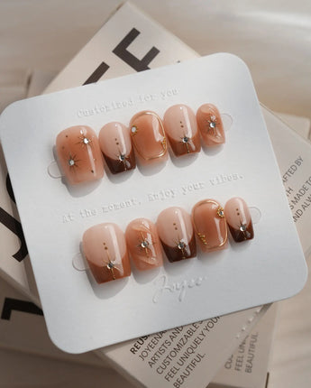 Fall Makeup nail design with brown ombre, metallic star linework, and sparkling gems
