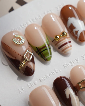 Close-up of THE HEIR press-on nails with vintage plaid, metallic horsebits and horse silhouettes