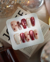 Coquette Red press-on nails with festive red chrome, gold bow details and romantic rose accents