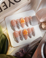 Sunset Shore glossy island nails with tropical flowers, seashell texture, and sunset shimmer