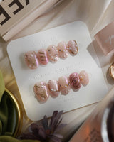 Neon Kiss press-on nails with pearly pink chrome, gold curves and sculpted butterfly accents