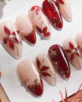 Close-up of Crimson Petals press-on nails with red French tips, gold outlines and floral details