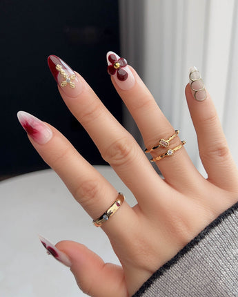 Tip Burgundy Nails with glossy burgundy tips, gold cross detail, and soft floral nail art