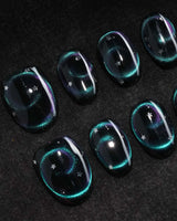 Absinthe press on nails in black with an emerald green cat eye halo and small silver star accents - image 1