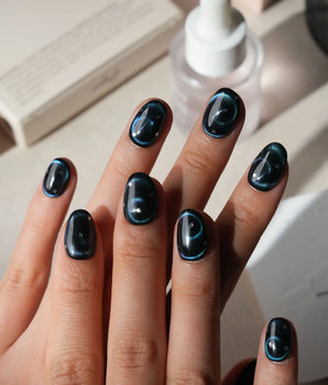 Absinthe press on nails in black with an emerald green cat eye halo and small silver star accents - image 2