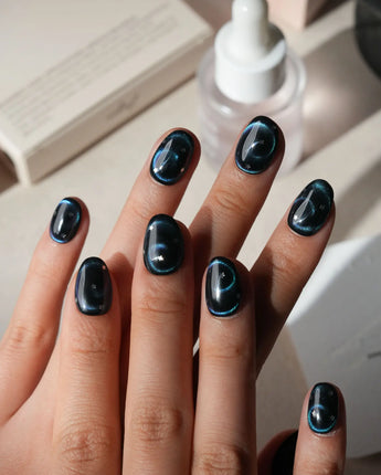 Absinthe press on nails in black with an emerald green cat eye halo and small silver star accents - image 2