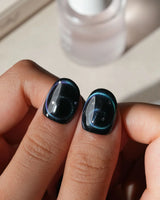 Absinthe press on nails in black with an emerald green cat eye halo and small silver star accents - image 4