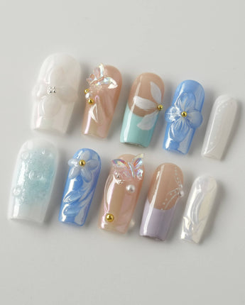 Aqua Petal medium square nails with pearly pastels, 3D flowers, and butterfly accents
