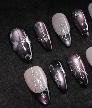 Arcana press on nails with sculpted silver sun, moon, star and key charms and a silver wing on plum and black cat eye with crystals - image 1