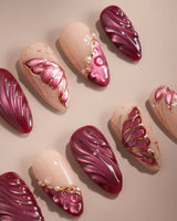 Close-up of Velvet Flow press-on nails with red cat-eye texture and outlined butterfly wings
