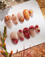 Close-up of Autumn Bounty press-on nails with 3D pumpkins, red apples and gold outlines