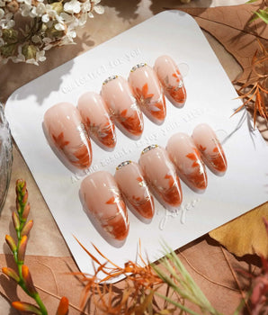 Amber Maple press-on nails with amber orange French tips and gold outlined maple leaves