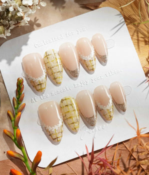 Tweed Light nail set with pale nude base, gold shimmer tips, and soft plaid accents