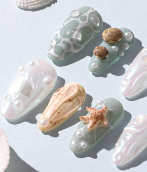 Mauritius Escape beach nails with iridescent white shimmer, shell accents, and pearl drops