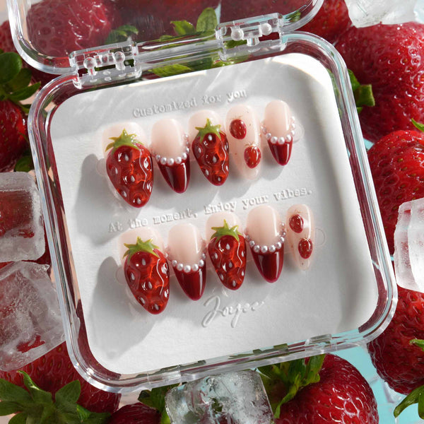 Close-up of glossy 3D strawberry nail art with pearl accents