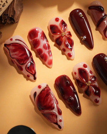 Bloody Kiss nail art close-up showing deep red marble nude base 3D flower chrome beads sculpted gel drip design details