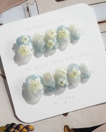 Bora Bora Blue extra short oval nails with blue ocean cat-eye and plumeria accents