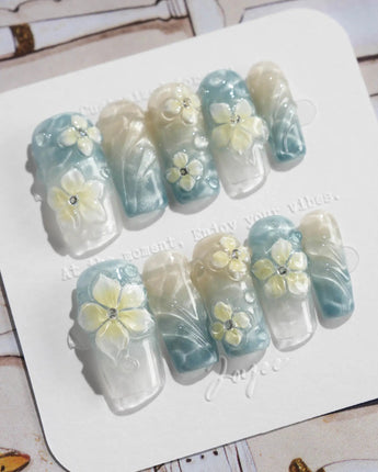 Bora Bora Blue medium square nails with cat-eye waves and white yellow floral sculpture