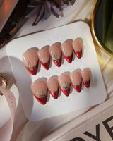 Bow French press-on nails in short stiletto shape — nude base red chrome french gold outline bow accent