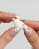 Call Duck Tutu custom-size short almond nails with white bows and mini wildflowers