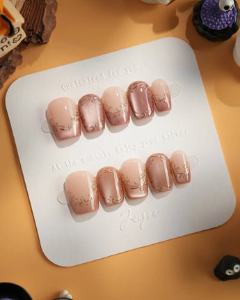 Caramel Petal press-on nails with nude base, mauve chrome French tips and ornate gold accents