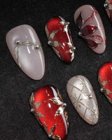 Carmine Court press on nails with sculpted gold leaves and silver pearls on deep red cat eye and a gold lattice on nude nails - image 1