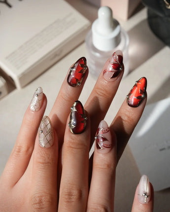 Carmine Court press on nails with sculpted gold leaves and silver pearls on deep red cat eye and a gold lattice on nude nails - image 2