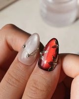 Carmine Court press on nails with sculpted gold leaves and silver pearls on deep red cat eye and a gold lattice on nude nails - image 4