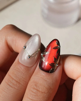 Carmine Court press on nails with sculpted gold leaves and silver pearls on deep red cat eye and a gold lattice on nude nails - image 4
