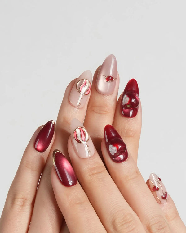 Cat-eye red nails with gold line and sculpted gel apple design