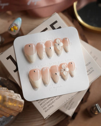 Ceramic press-on nails in short stiletto shape — Classic Nude Pink Ombré, 3D White Florals & Minimalist Rhinestones.