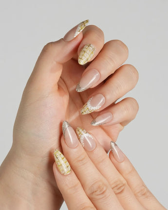 Close-up of Tweed Light nails with yellow plaid, gold French tips, and lace-inspired detail