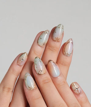 Pastel Relic nail set with milky champagne shimmer, delicate gold lines, and starburst details