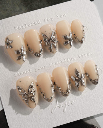 Chrome Rebellion press-on nails in extra short almond shape — Nude, 3D Silver Butterflies & Liquid Metal.