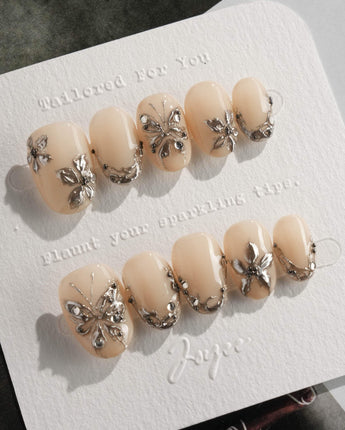 Chrome Rebellion press-on nails in extra short oval shape — Nude, 3D Silver Butterflies & Liquid Metal.