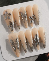 Chrome Rebellion press-on nails in long stiletto shape — Nude, 3D Silver Butterflies & Liquid Metal.