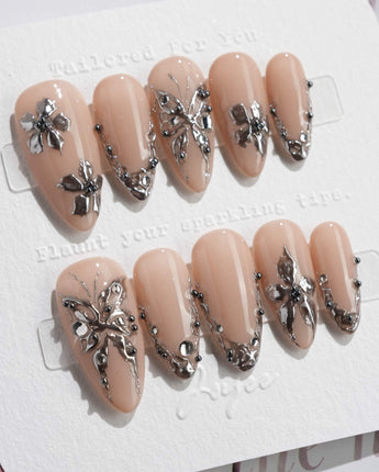 Chrome Rebellion press-on nails in medium almond shape — Nude, 3D Silver Butterflies & Liquid Metal.
