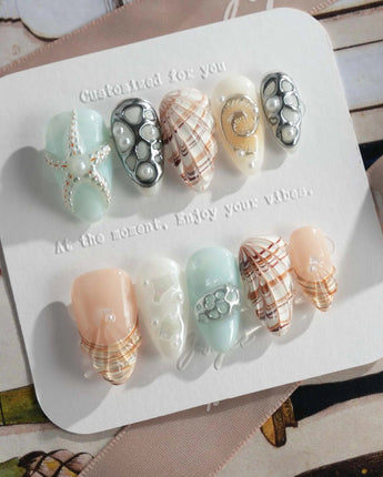 Coastline Edit moody summer nails with silver shells and brown-gold shimmer