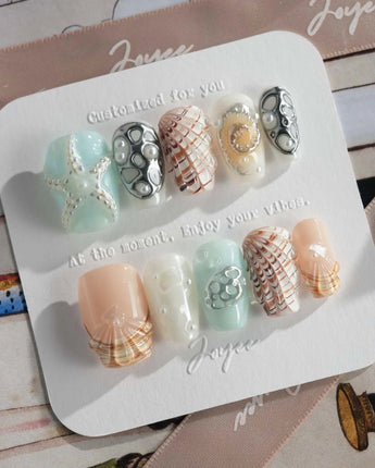 Coastline Edit hand-painted ocean nails with starry spiral and shell details