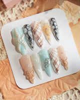 Coastline Edit seashell nail art with azure nude polish and metallic accents