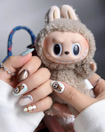 CocoaBoo Labubu close-up of brown chrome, plaid nail art, and playful collectible-inspired face