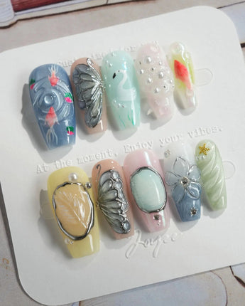 Como Blue medium coffin nails with pearly pastels, goldfish, and sculpted butterfly art