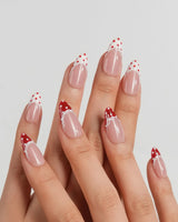 Coquette Dot blush nude nails with deep red dotted tips, gel bows and lace trim