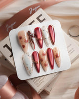 Coquette Red long stiletto press-on nails with deep red chrome, gold outlines, bows, and rose accents