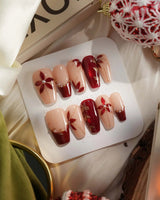 Crimson Petals press-on nails with nude base, red French tips and gold outline florals